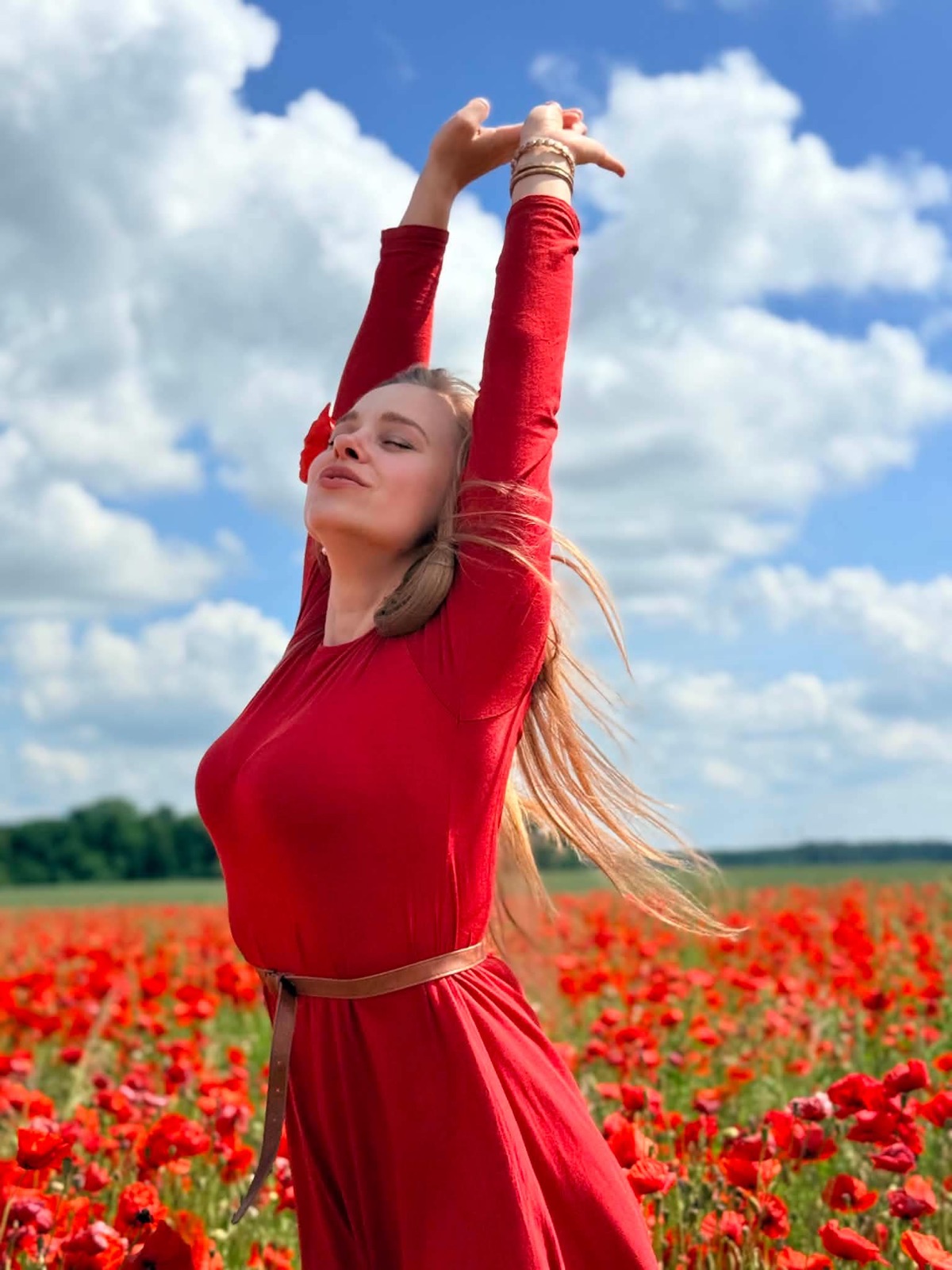 Agnė aguonų lauke iškėlusi rankas į dangų