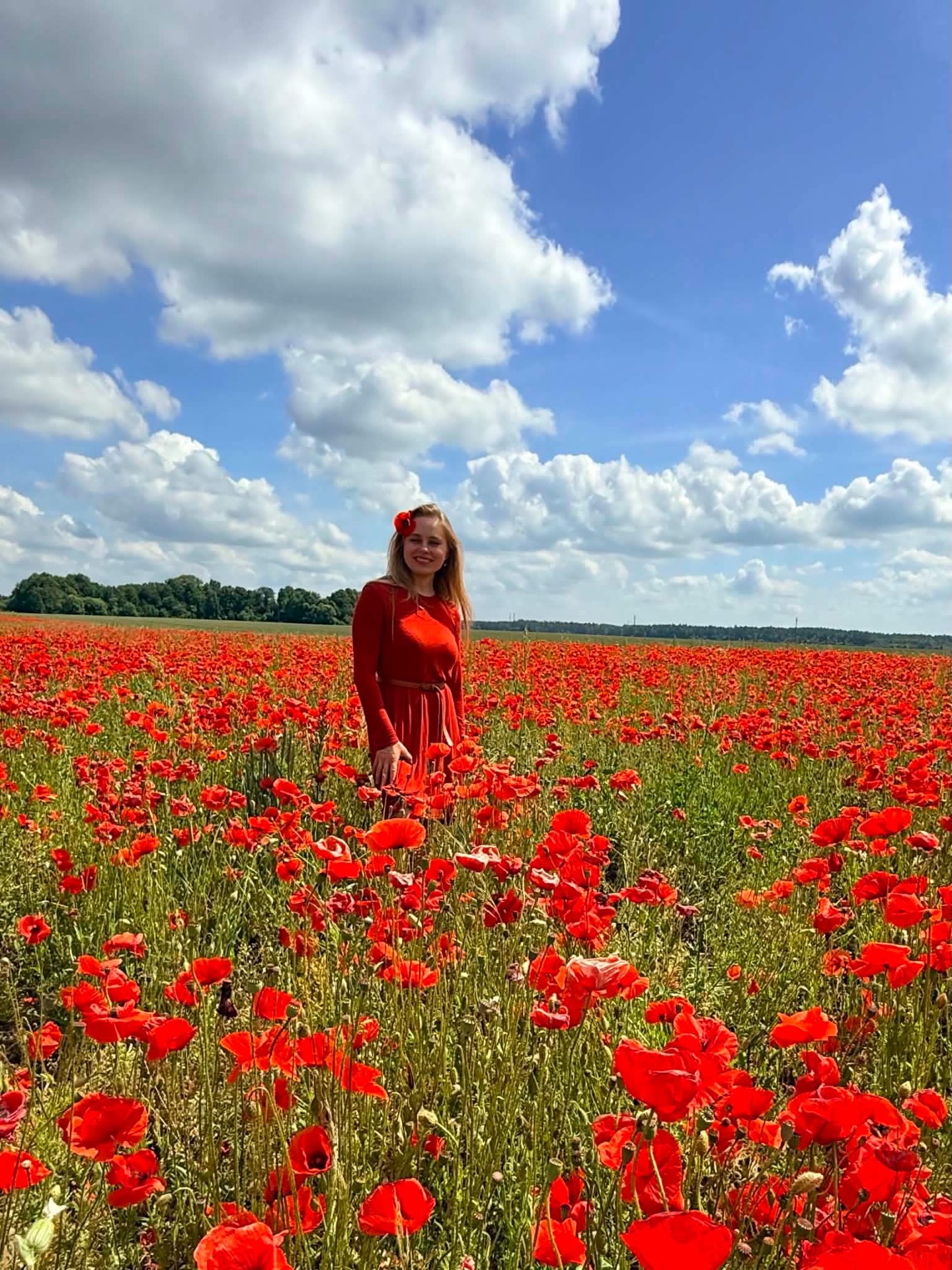 Agnė raudona suknele plačiame žydinčiame aguonų lauke