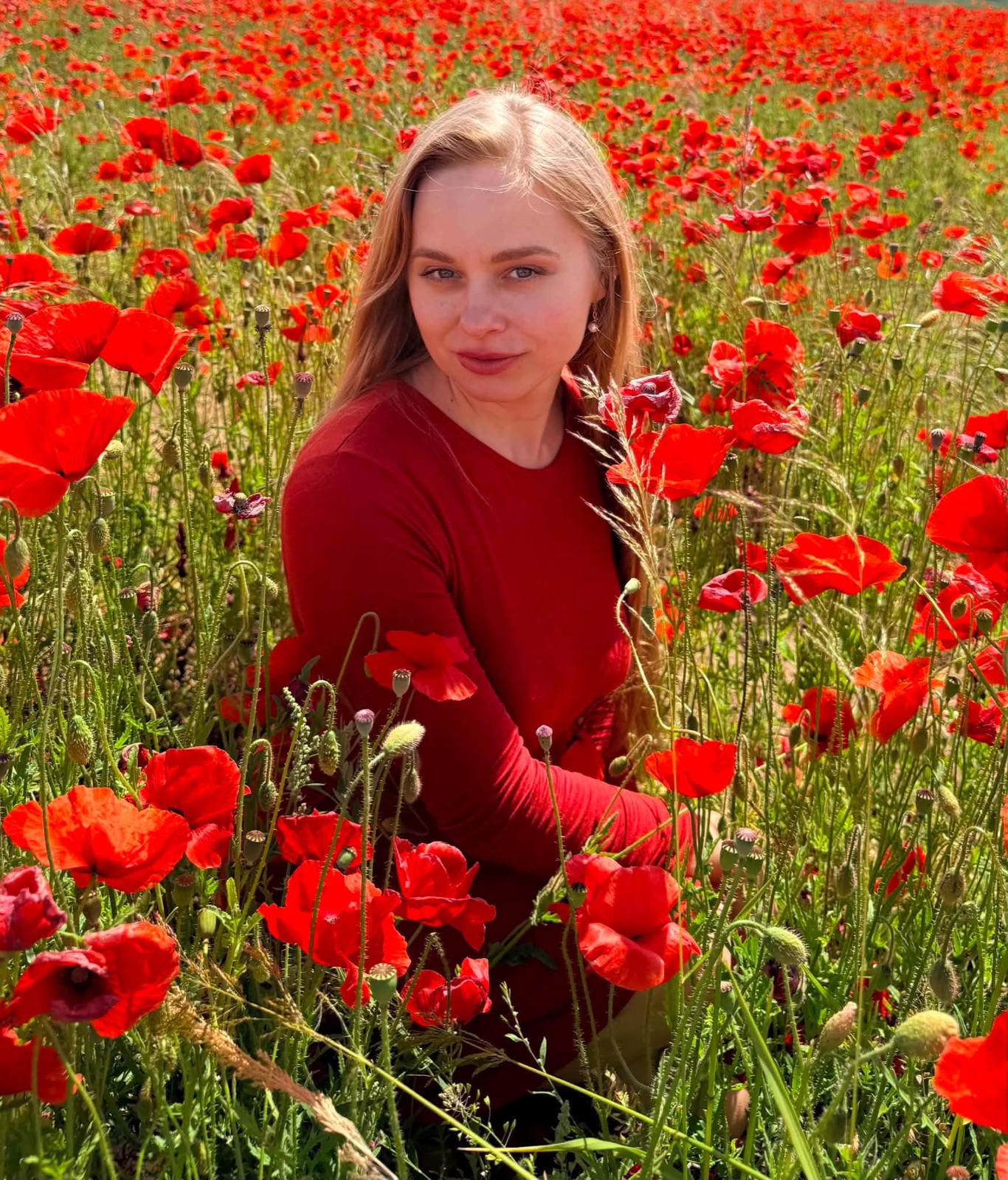 Agnė Melanija aguonų lauke, žvelgianti tiesiai į tave